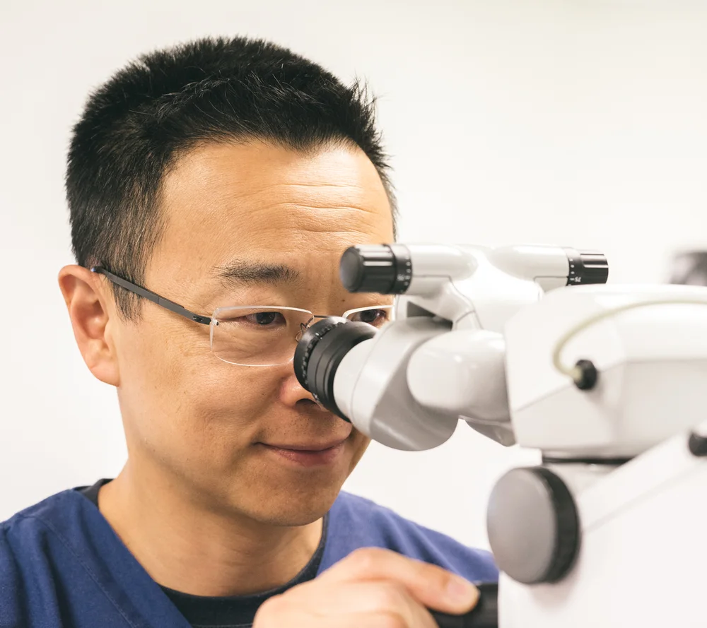 Dr Simon Chen using a surgical microscope